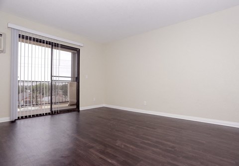 an empty living room with wood floors and a sliding glass door